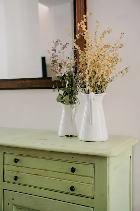 Recibidor con cómoda verde y flores secas
